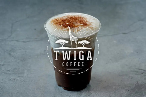 A clear cup of iced coffee topped with a layer of cold foam and a dusting of cocoa.